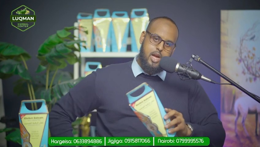 A man holding a product box in front of shelves of herbal preparations
