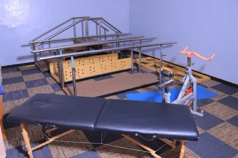 Rehabilitation area with parallel walking bars, exercise bike and plinth